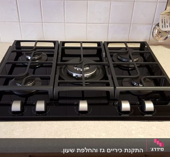 כיריים גז שחורות עם חמישה מבערים וכפתורי שליטה כסופים